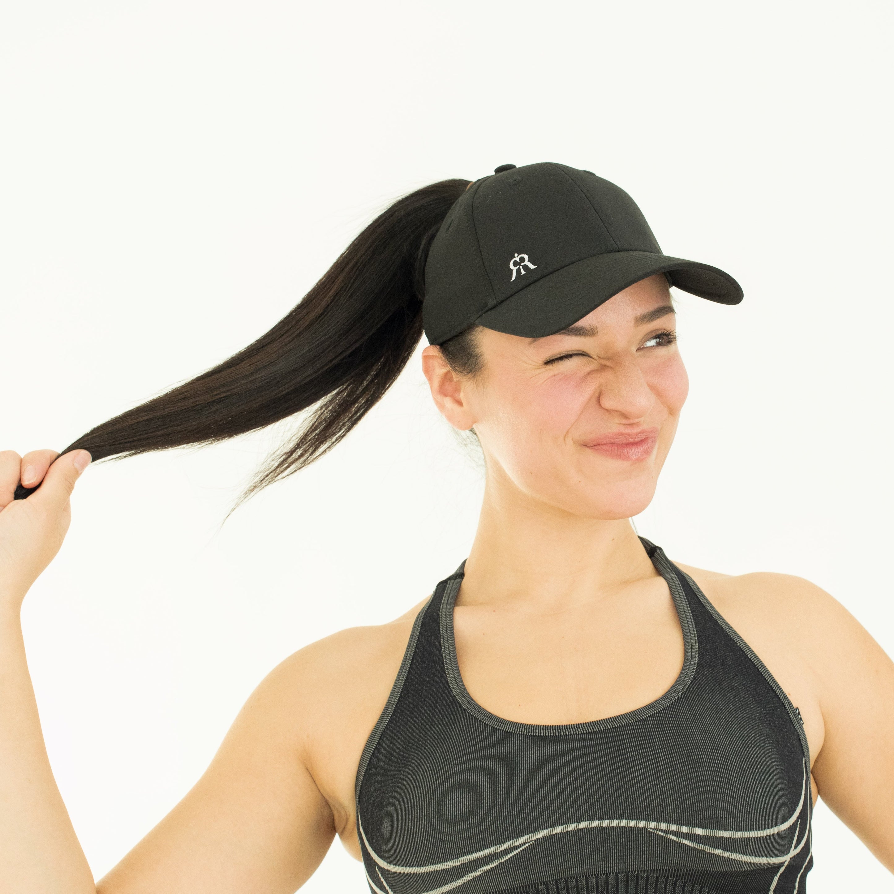 Model smiling in ponytail cap, white studio background