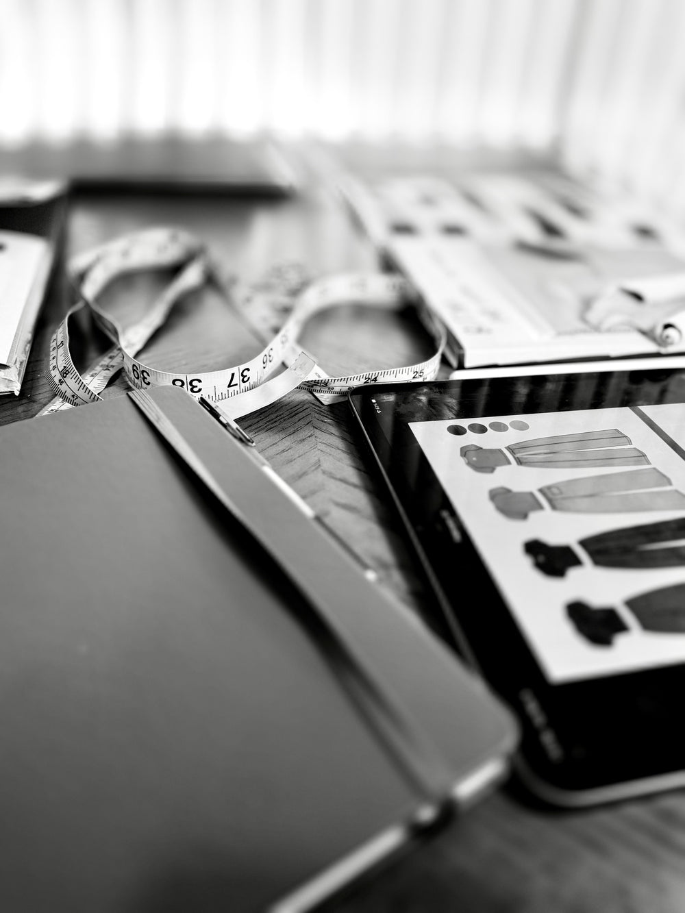 Fabric swatches, a measuring tape, and clothing sketches on a design table