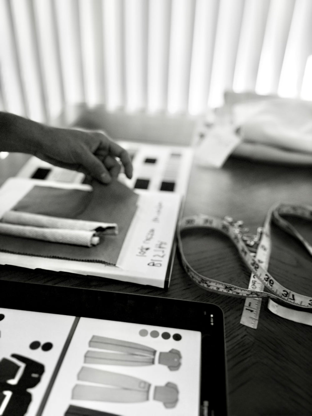 Selecting fabric swatches beside garment sketches on a design table