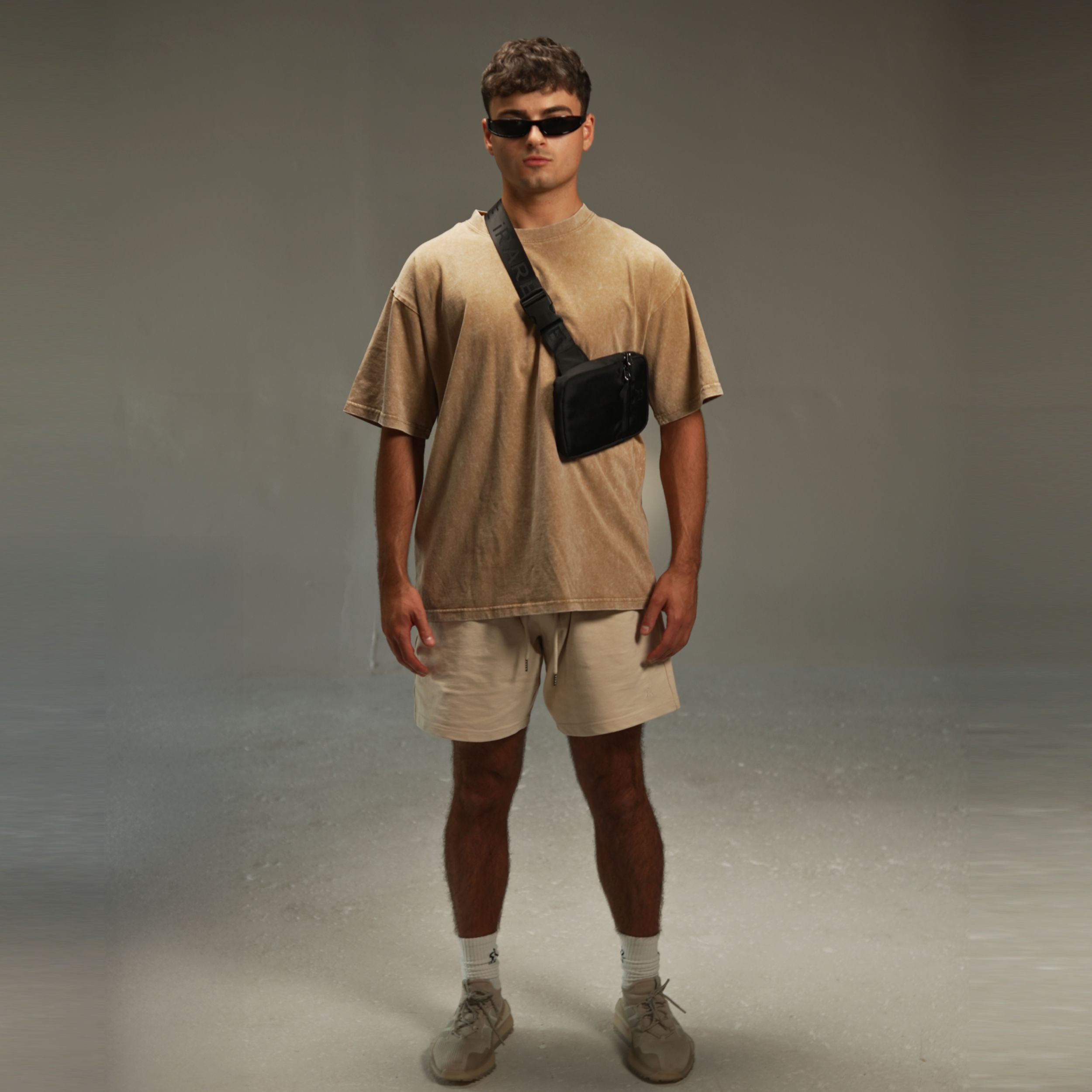 men’s acid-washed t-shirt in washed sand, styled look with crossbody bag