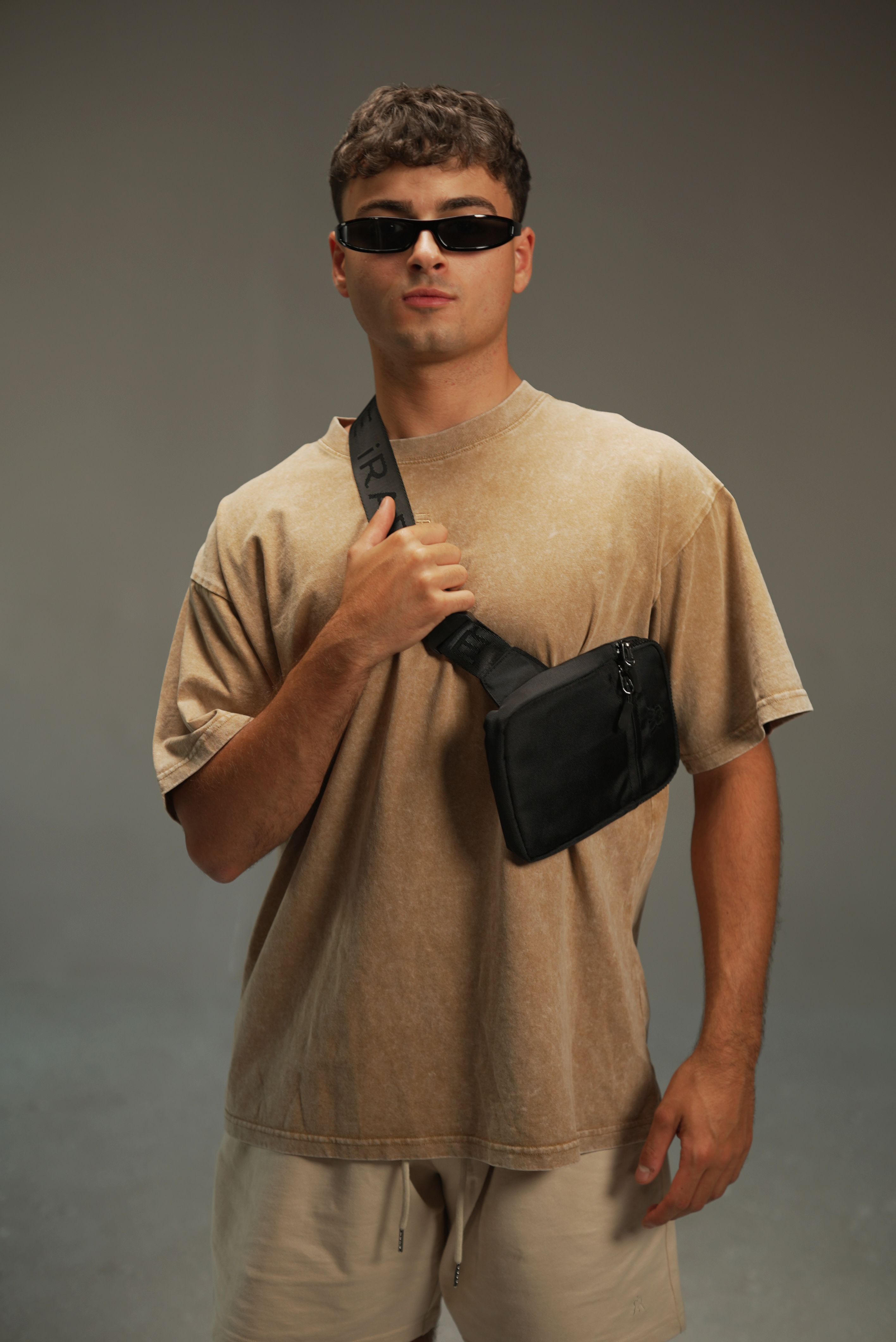 men’s acid-washed t-shirt in washed sand, styled look with crossbody bag