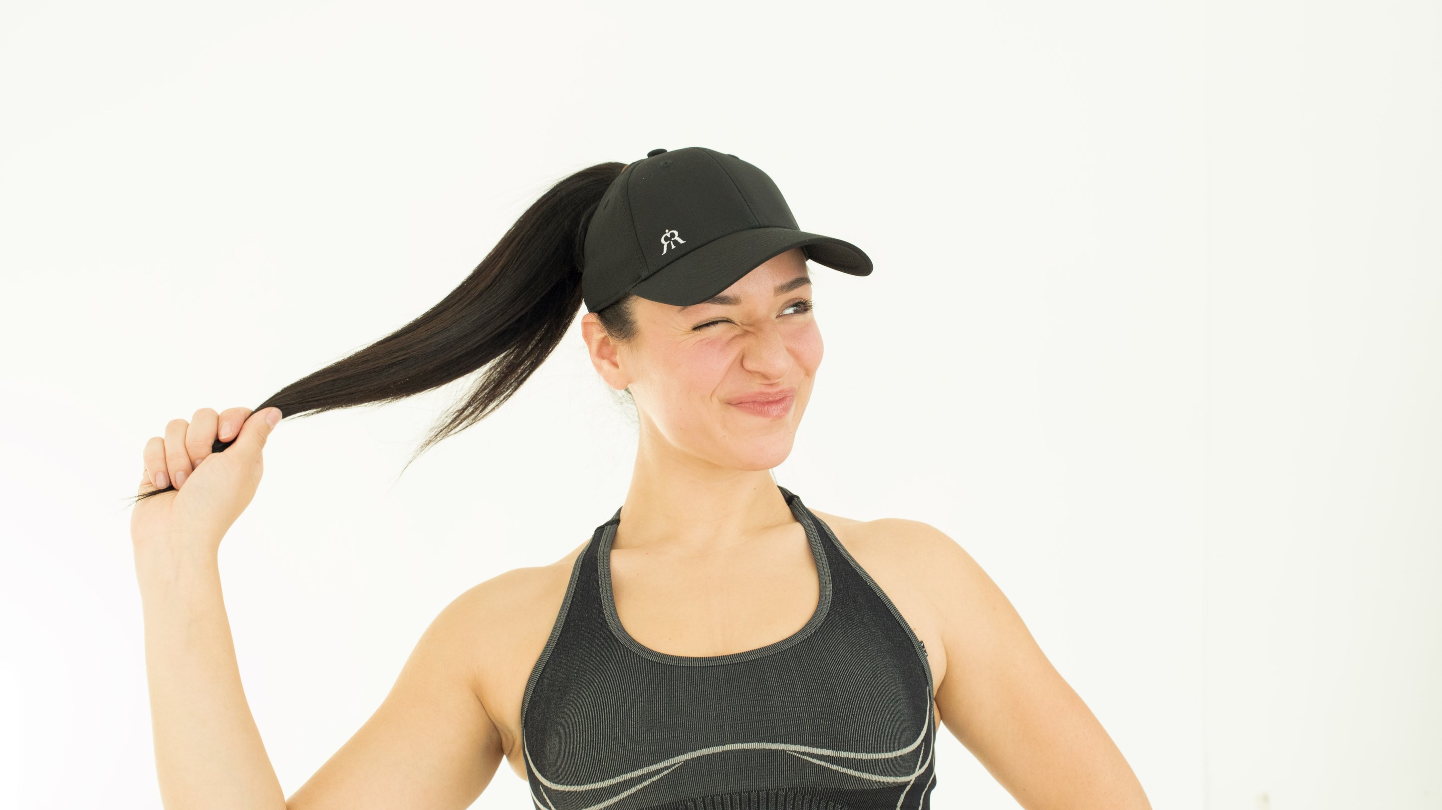 Model smiling in ponytail cap, white studio background
