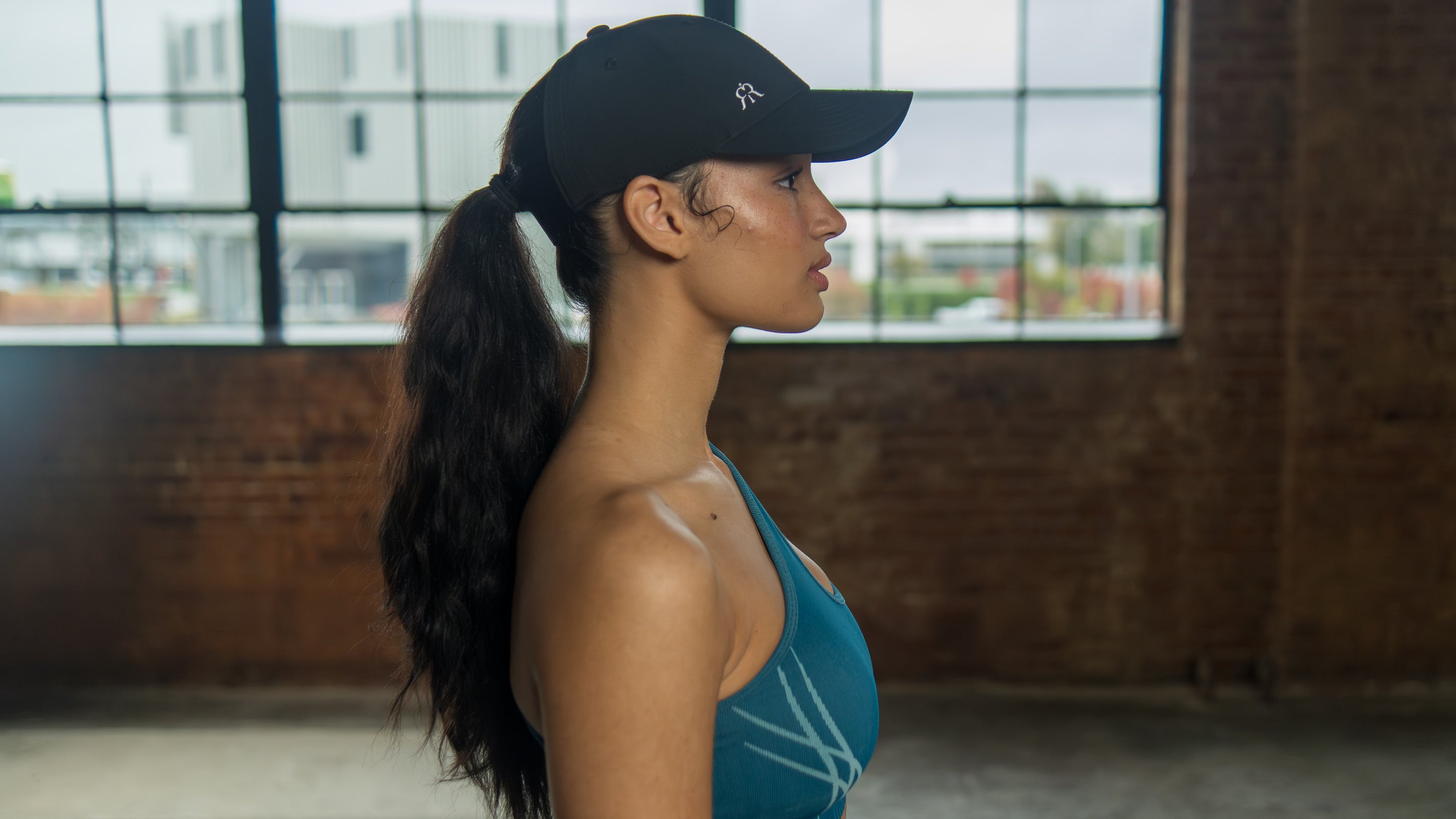 black ponytail cap worn on model, side view