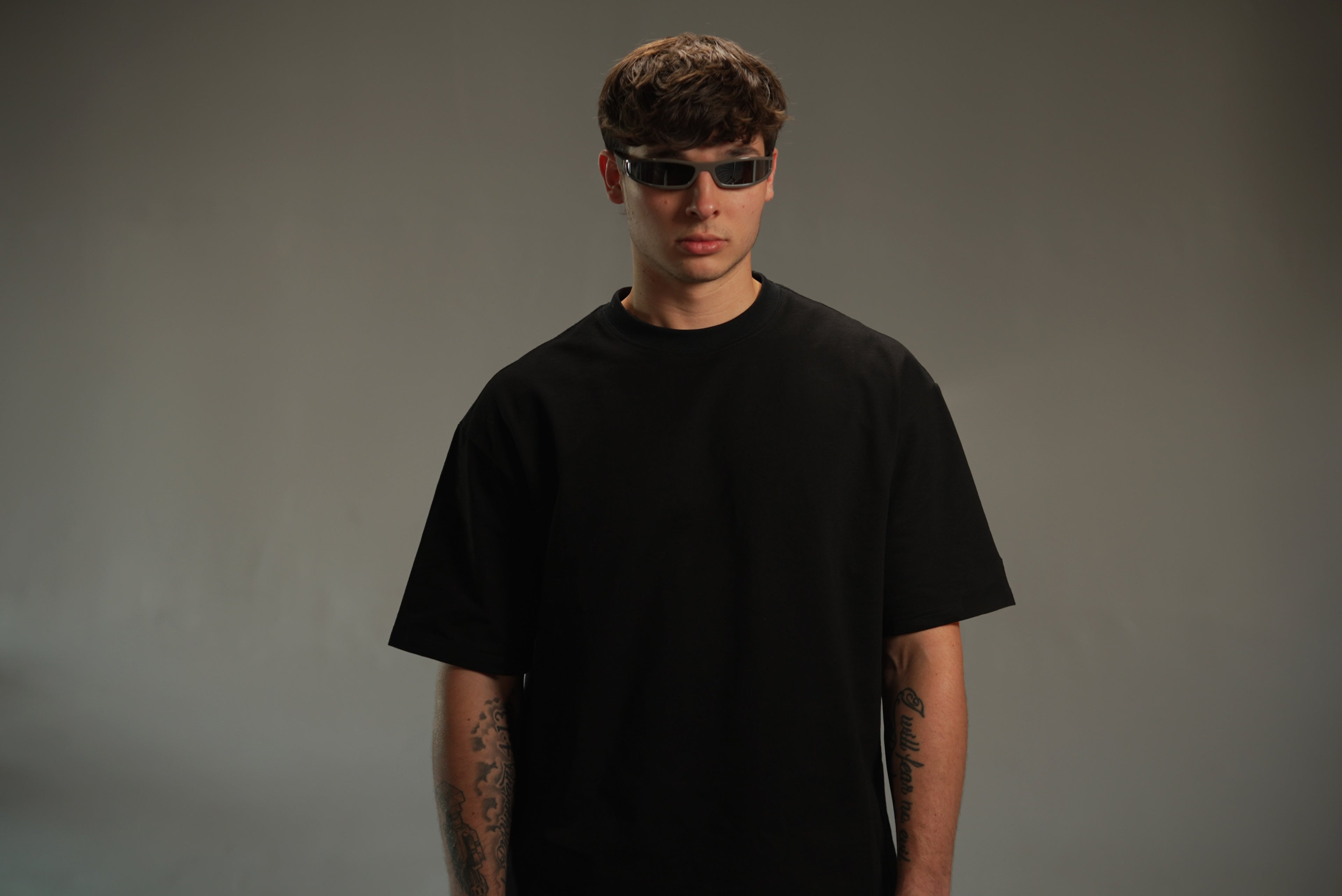 Model wearing a black iRARE oversized t-shirt styled in a minimal studio setting